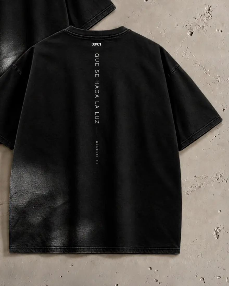 Camiseta Primera Luz negra lavada vista de espalda, con Que se haga la luz en vertical y 00:01 en la nuca
